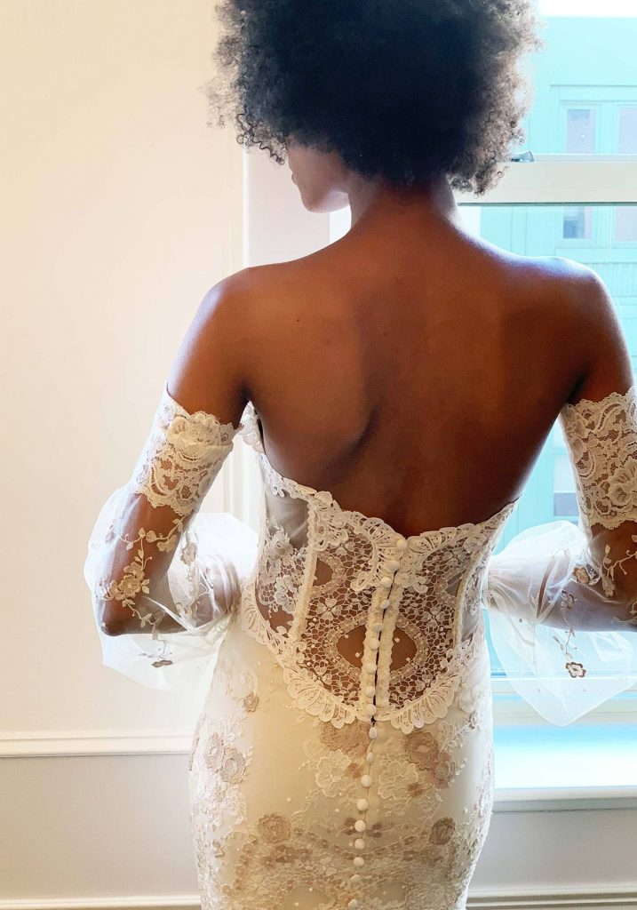 Black bride wears strapless dress with lace back and detachable lace sleeves. 