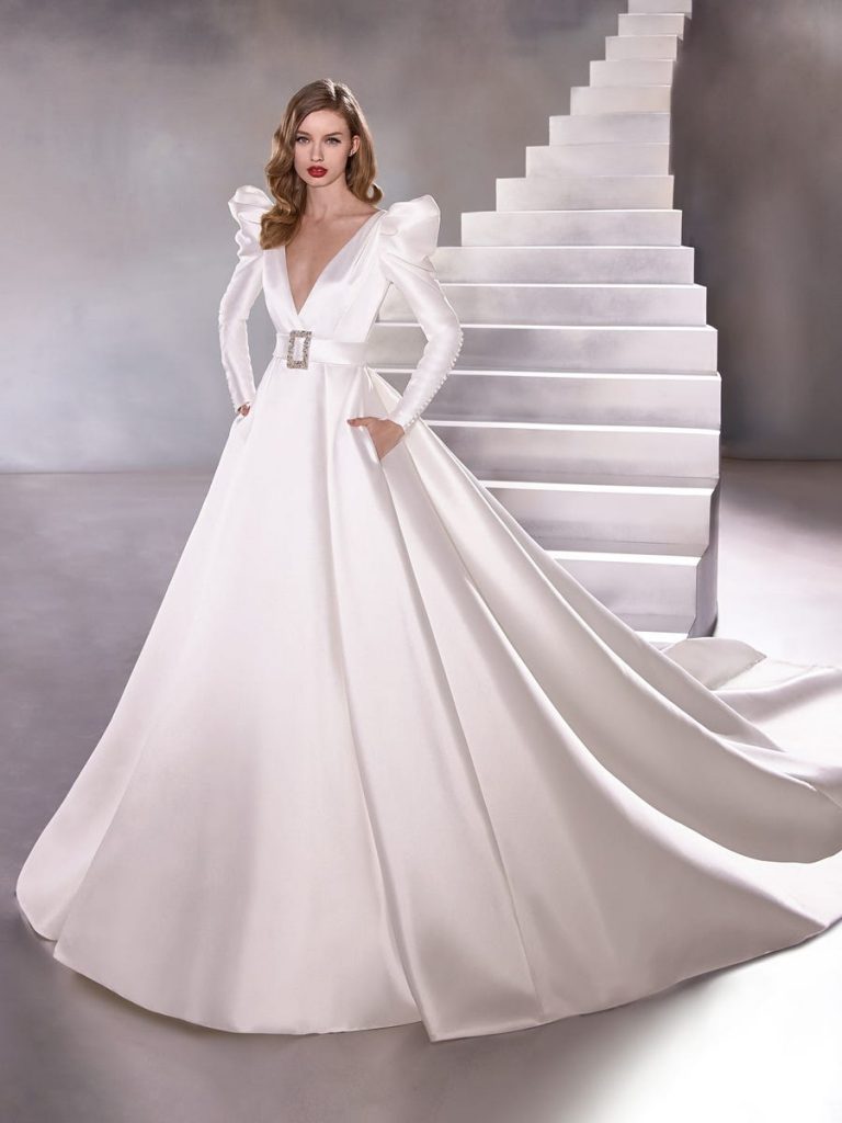 Winter wedding gown with 80s shoulders, long sleeves and buttons up to the elbow, belted waist and ball gown skirt. 